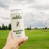 Caddie Breakfast Beer held with golfers teeing off in background