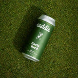 A green and silver can of caddie Early Bird Session IPA lies diagonally on a textured green grass surface.
