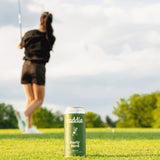 A green can of Caddie Early Bird sitting on fairway with golfer in background